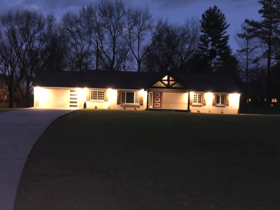 A house is lit up at night with trees in the background
