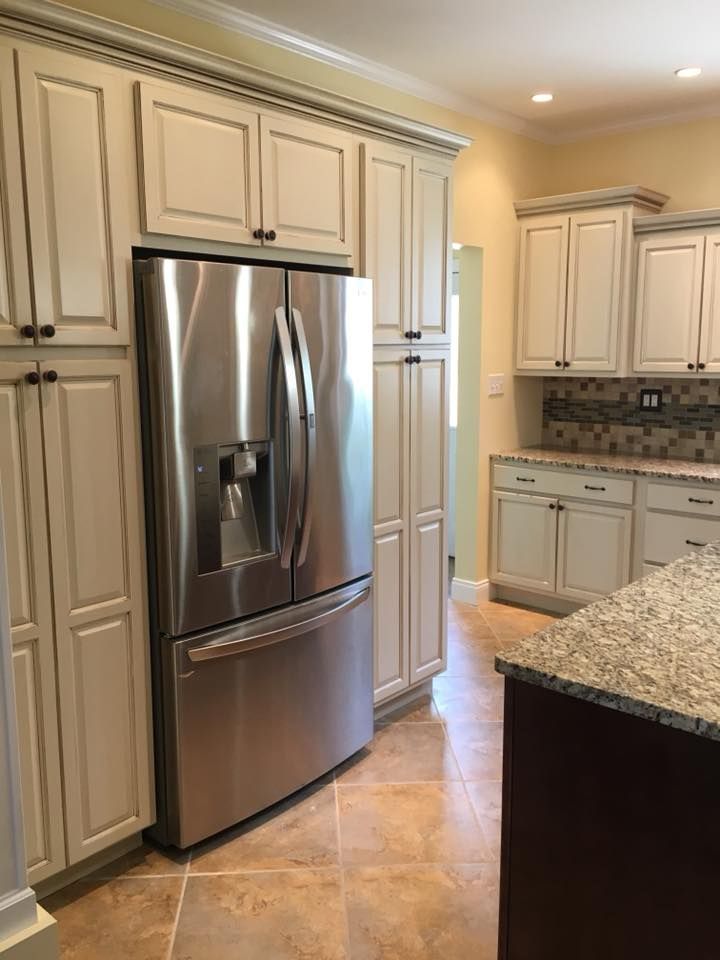 A kitchen with white cabinets and a stainless steel refrigerator.