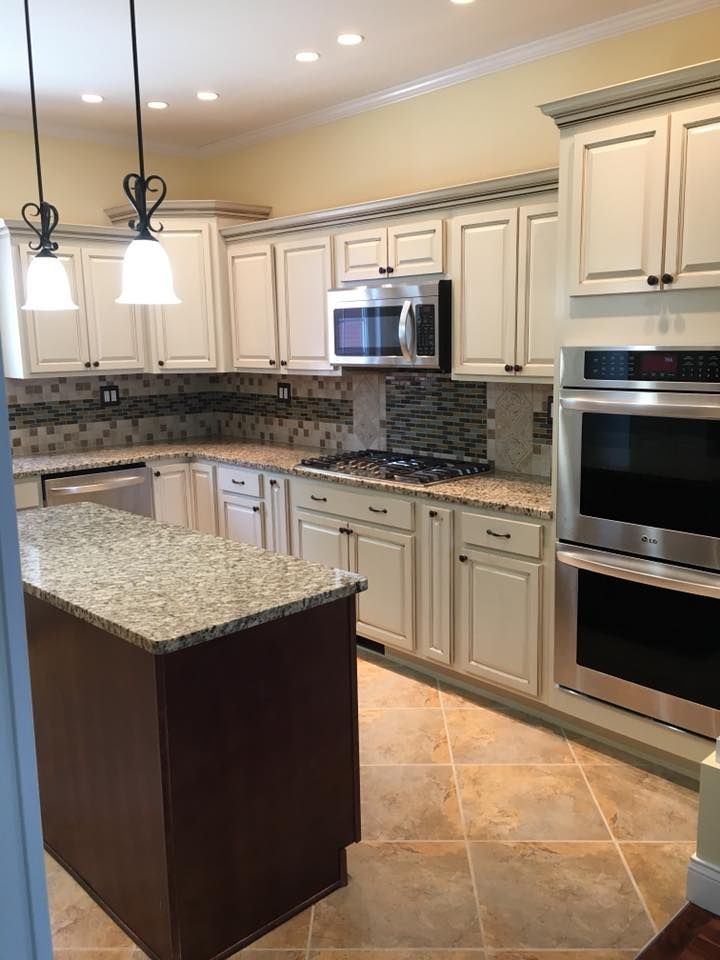 A kitchen with white cabinets , granite counter tops , stainless steel appliances and a large island.