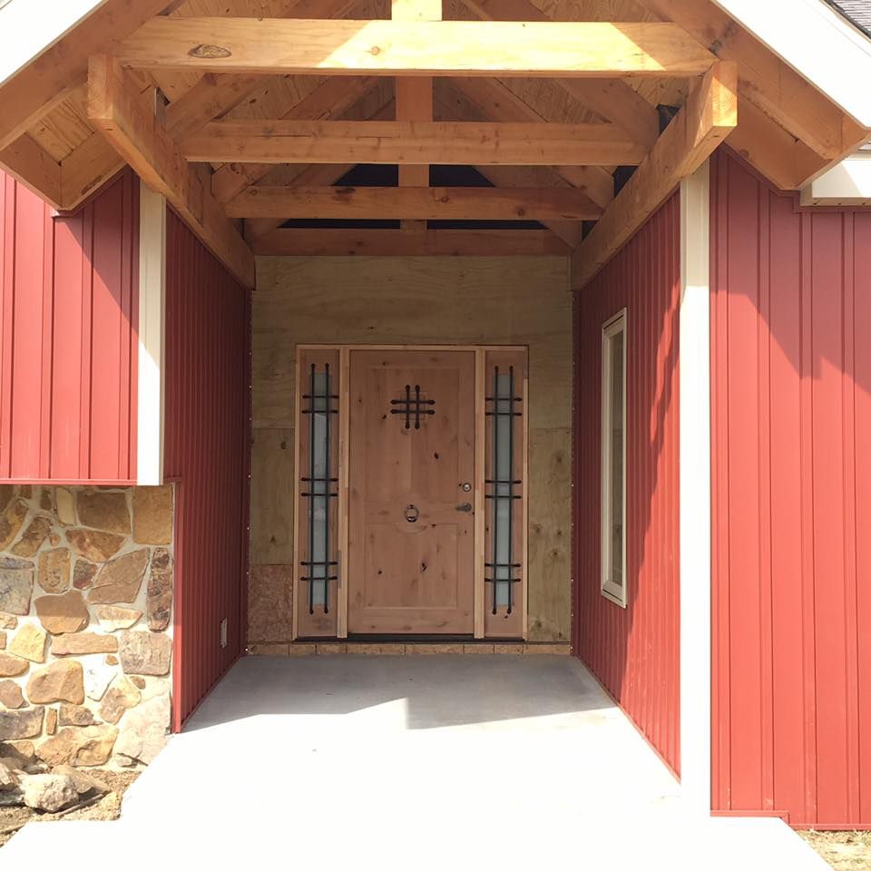 A red house has a wooden door with a cross on it