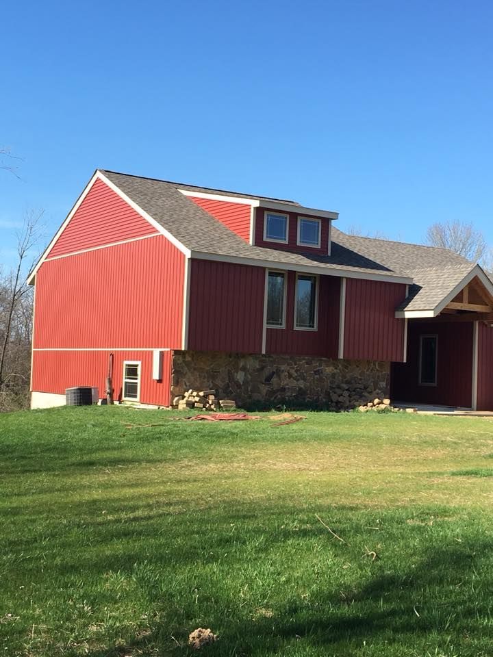 A large red barn sits in the middle of a grassy field