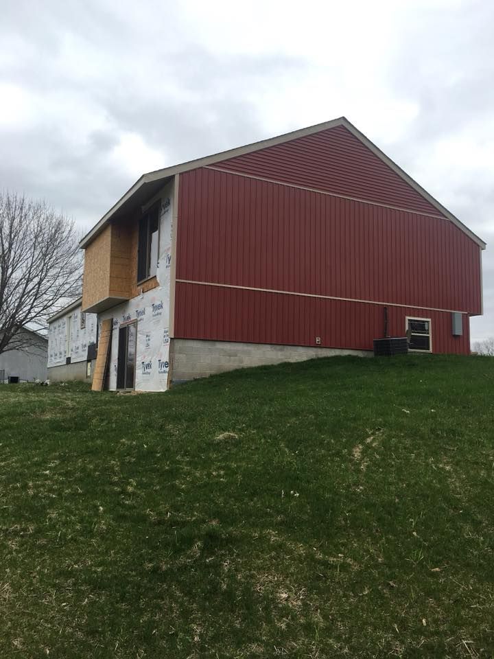 A red barn is sitting on top of a grassy hill.