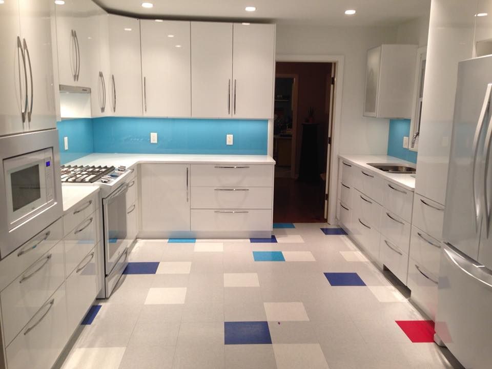 A kitchen with white cabinets and blue and red tiles