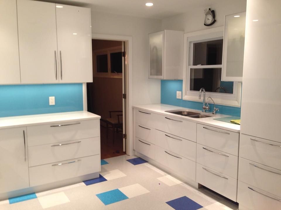 A kitchen with white cabinets and blue tiles