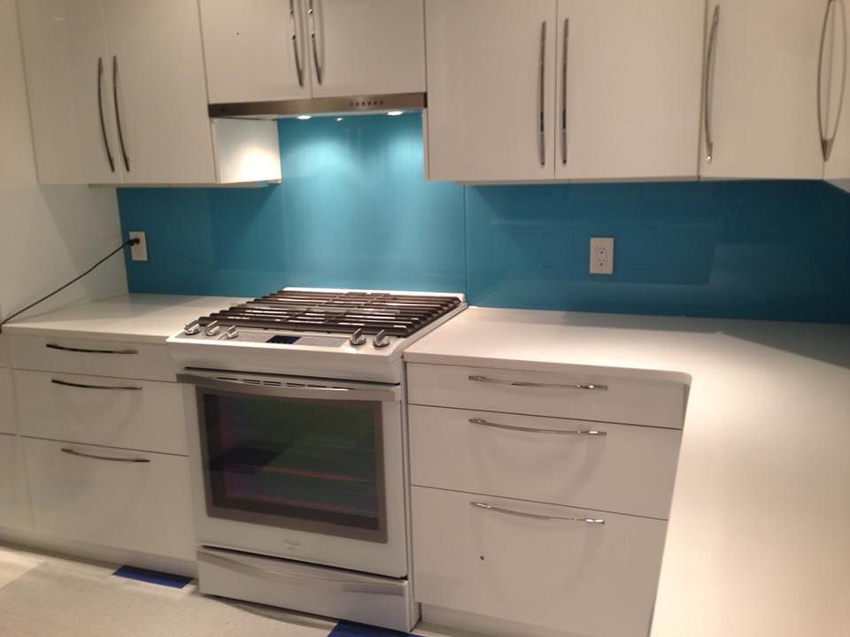 A kitchen with white cabinets and a blue backsplash