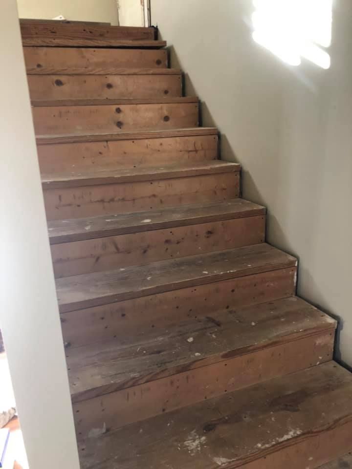A wooden staircase with a white wall in the background.