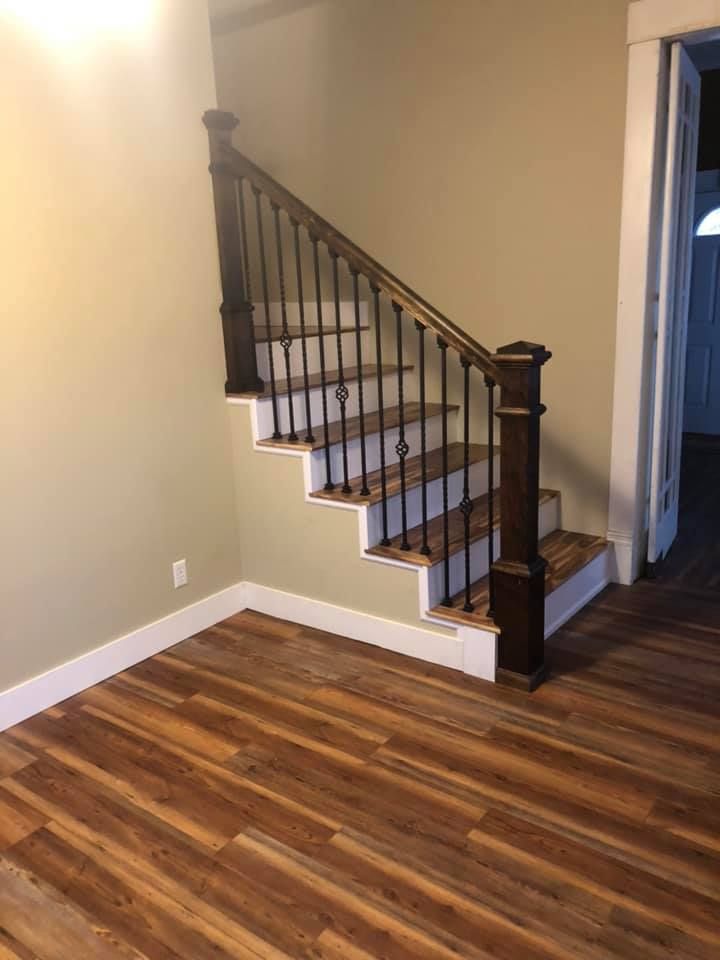 A staircase with wooden steps and a metal railing in a room with hardwood floors.