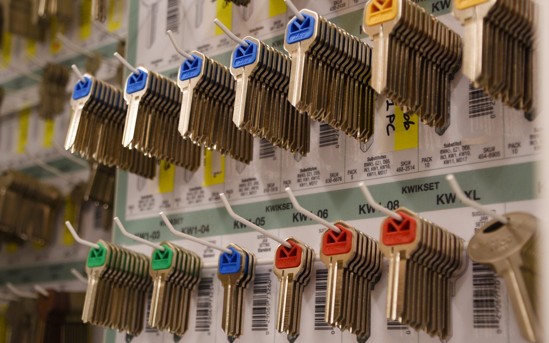 A bunch of keys are hanging on hooks on a wall.