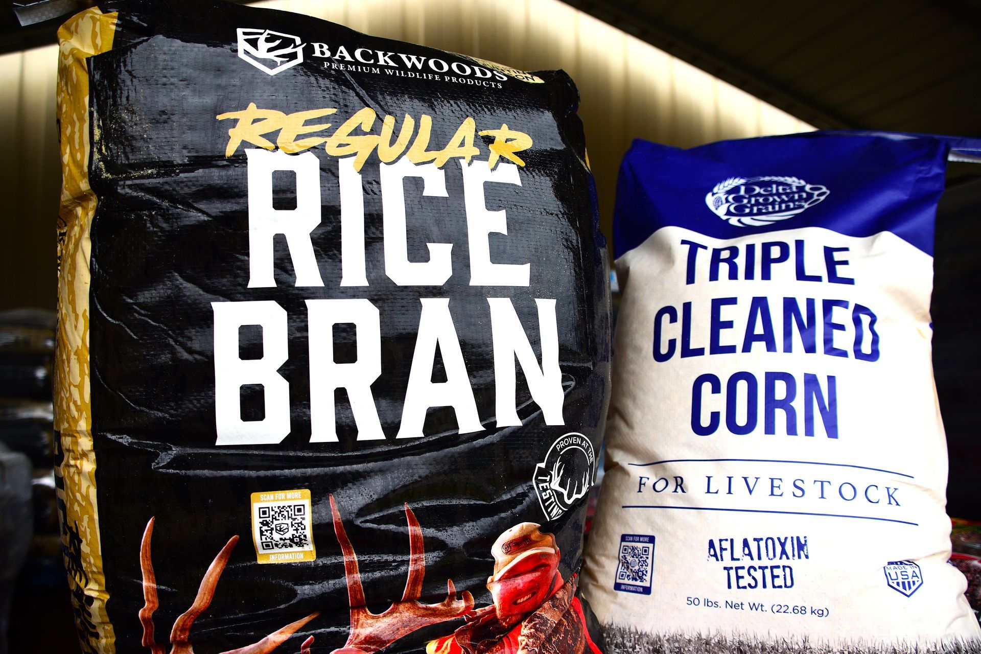 Two bags of pet food: black regular rice bran and blue-white triple cleaned corn.