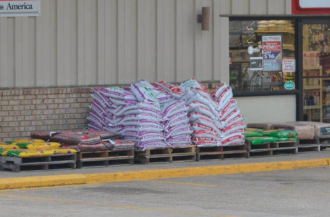A bunch of bags are stacked on pallets outside of a store