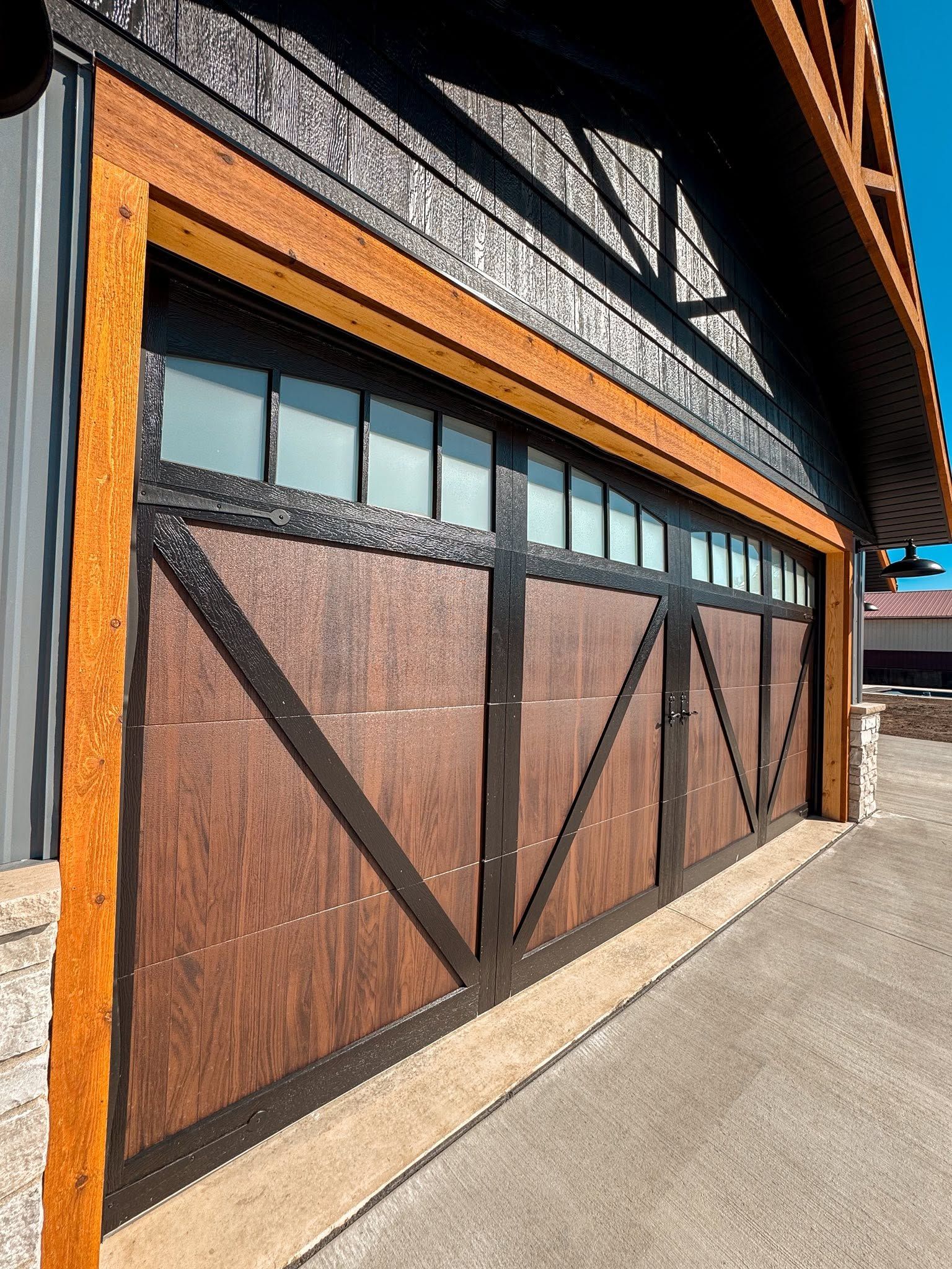 Rustic wooden barn-style garage doors on a building exterior in bright sunlight