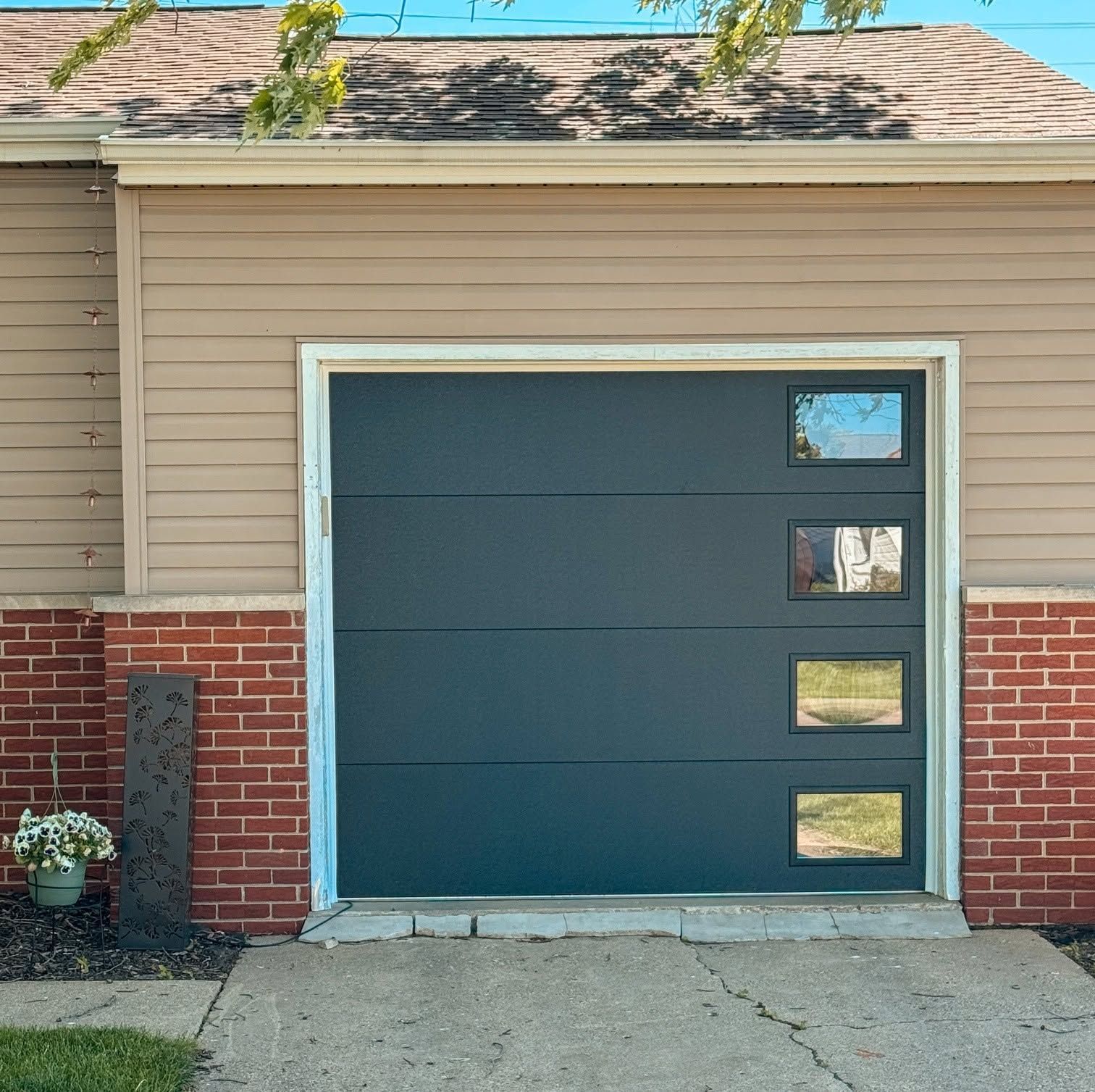 Blue garage door set in a beige-and-brick house exterior with four small windows on the right side.