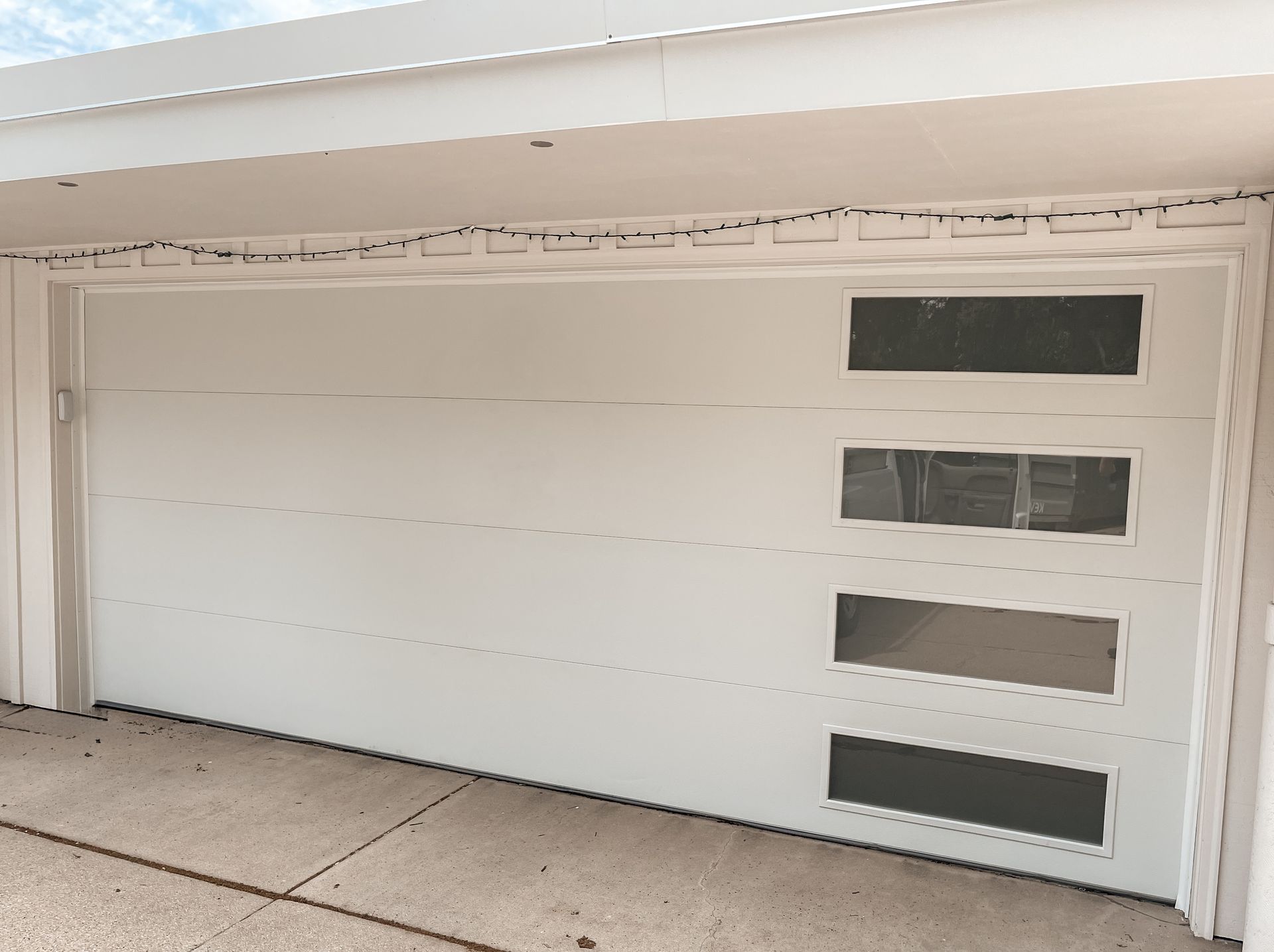 White modern garage door with four narrow rectangular windows on the right side.