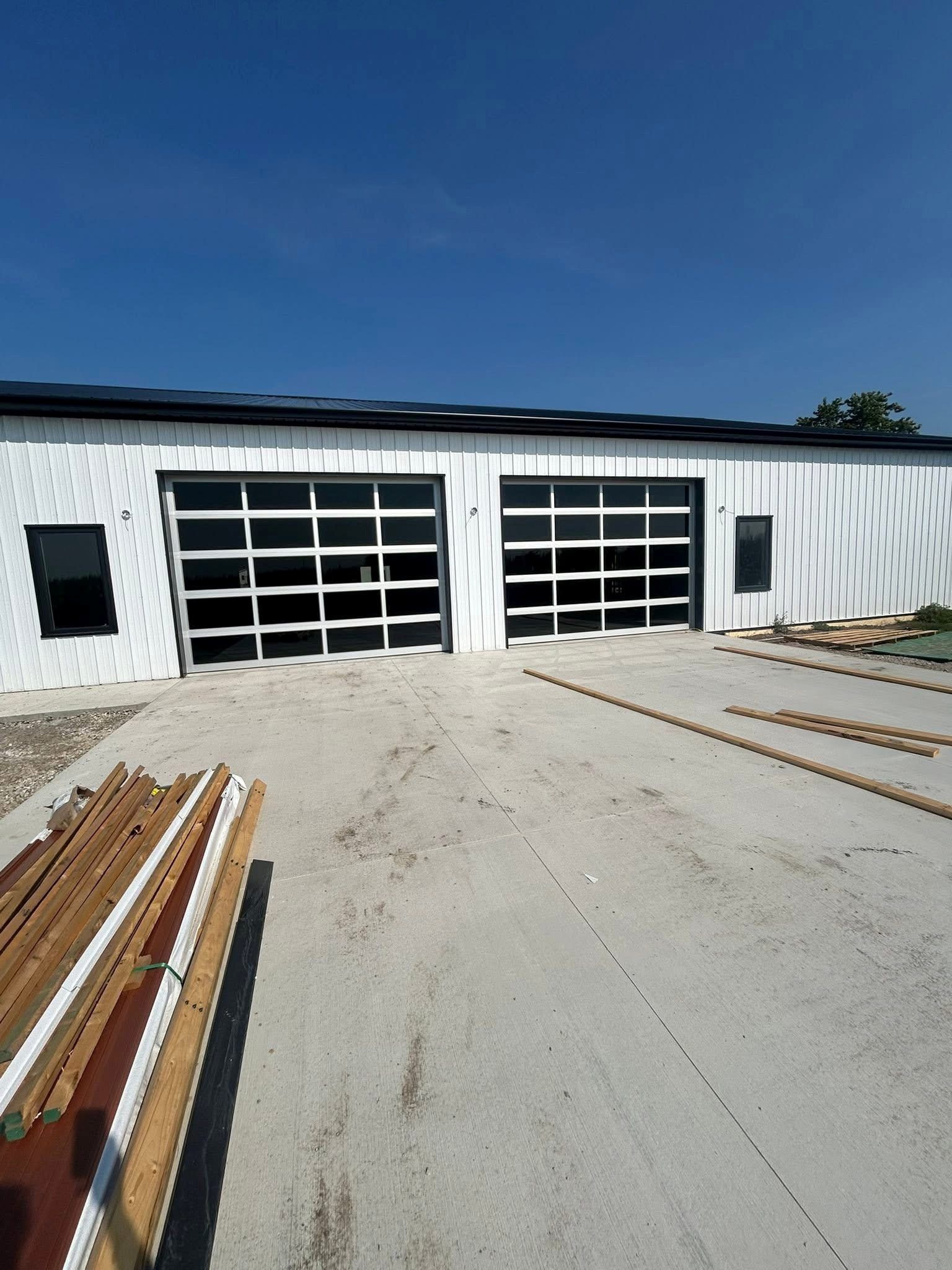 Exterior view of a white building with two glass garage doors, under a clear blue sky.