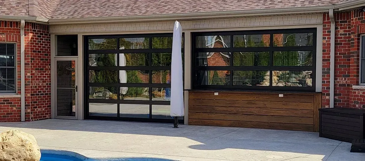 Patio with glass doors, brick exterior, and a wooden bar.  A folded umbrella stands on the patio.