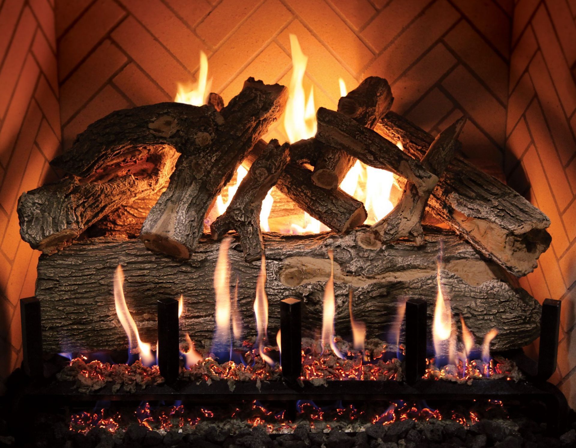 Burning logs in a brick fireplace with bright flames and glowing embers