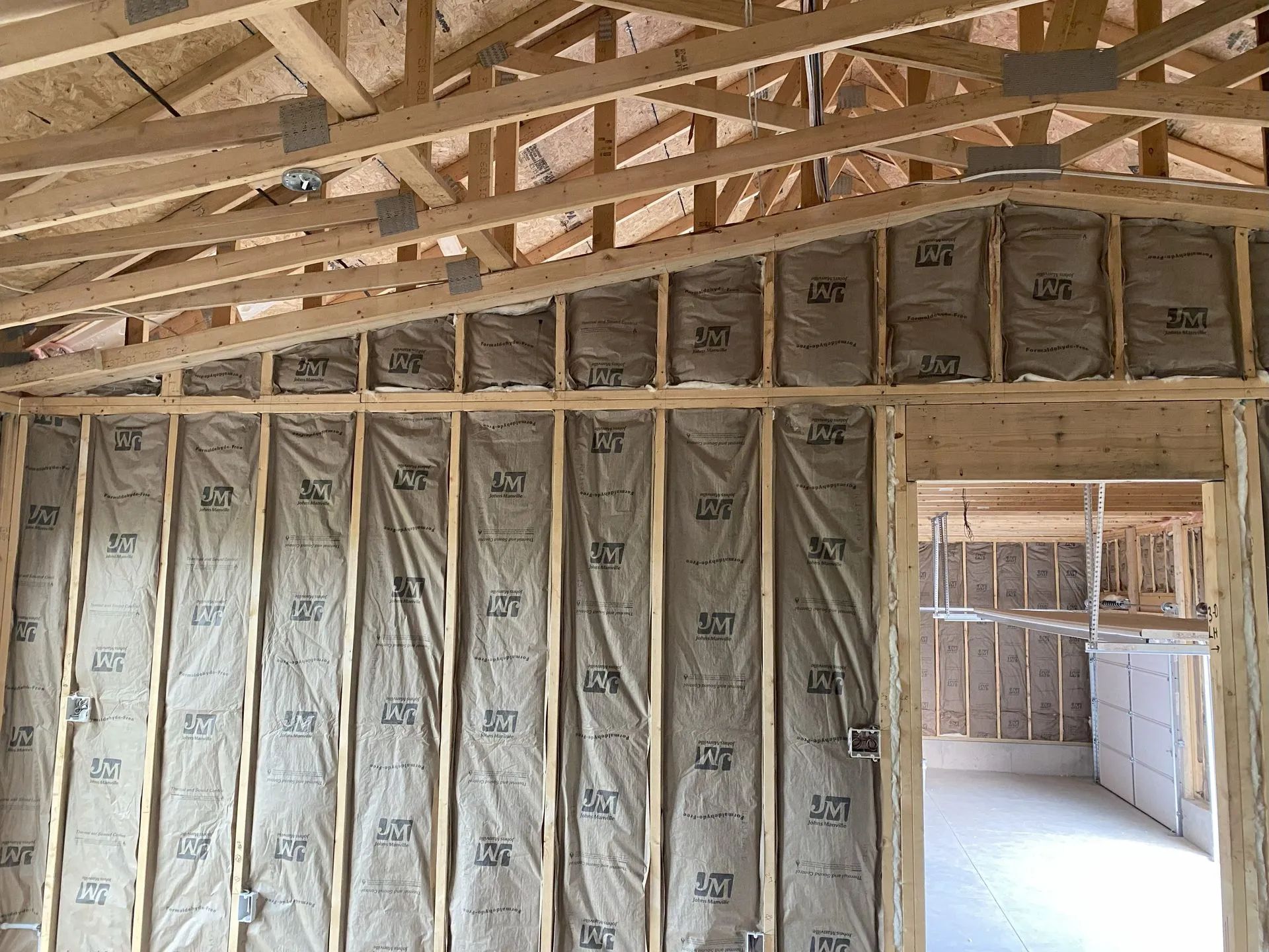 Unfinished house interior with exposed wood framing and insulation in the walls and ceiling.