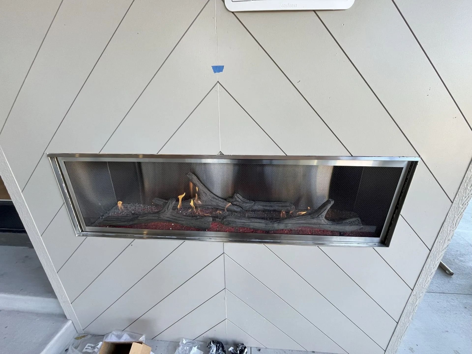 Modern white fireplace with a glass-front firebox and patterned tile surround