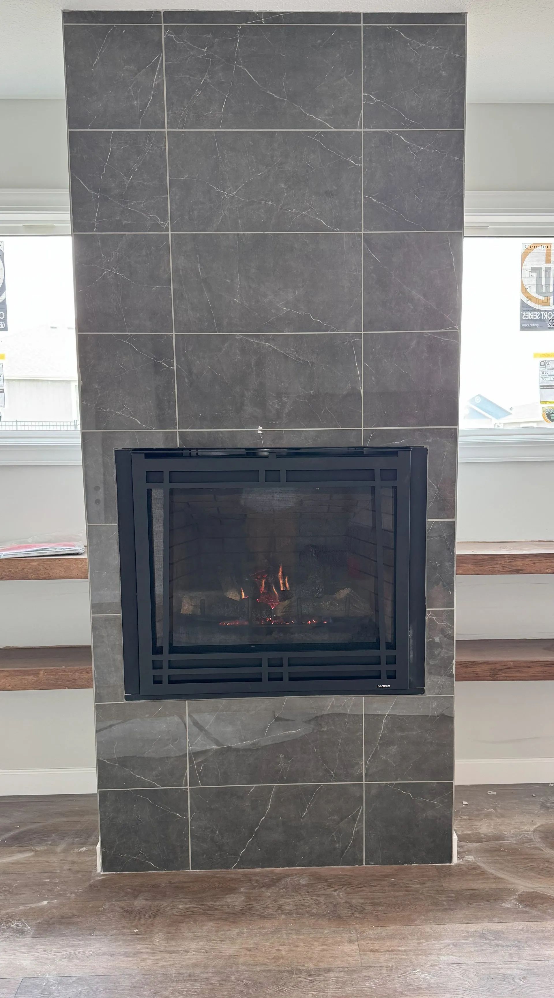 Black stone fireplace with a glass-front firebox in a bright indoor room