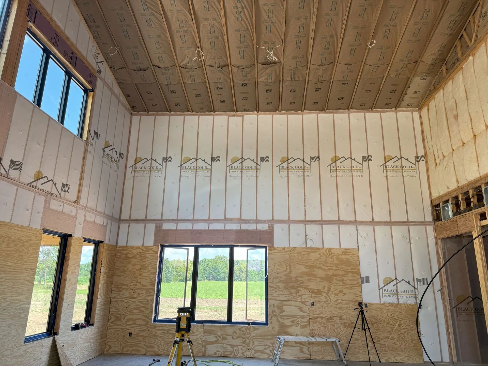 Partially finished room interior with exposed insulation, windows, and construction tools on the floor