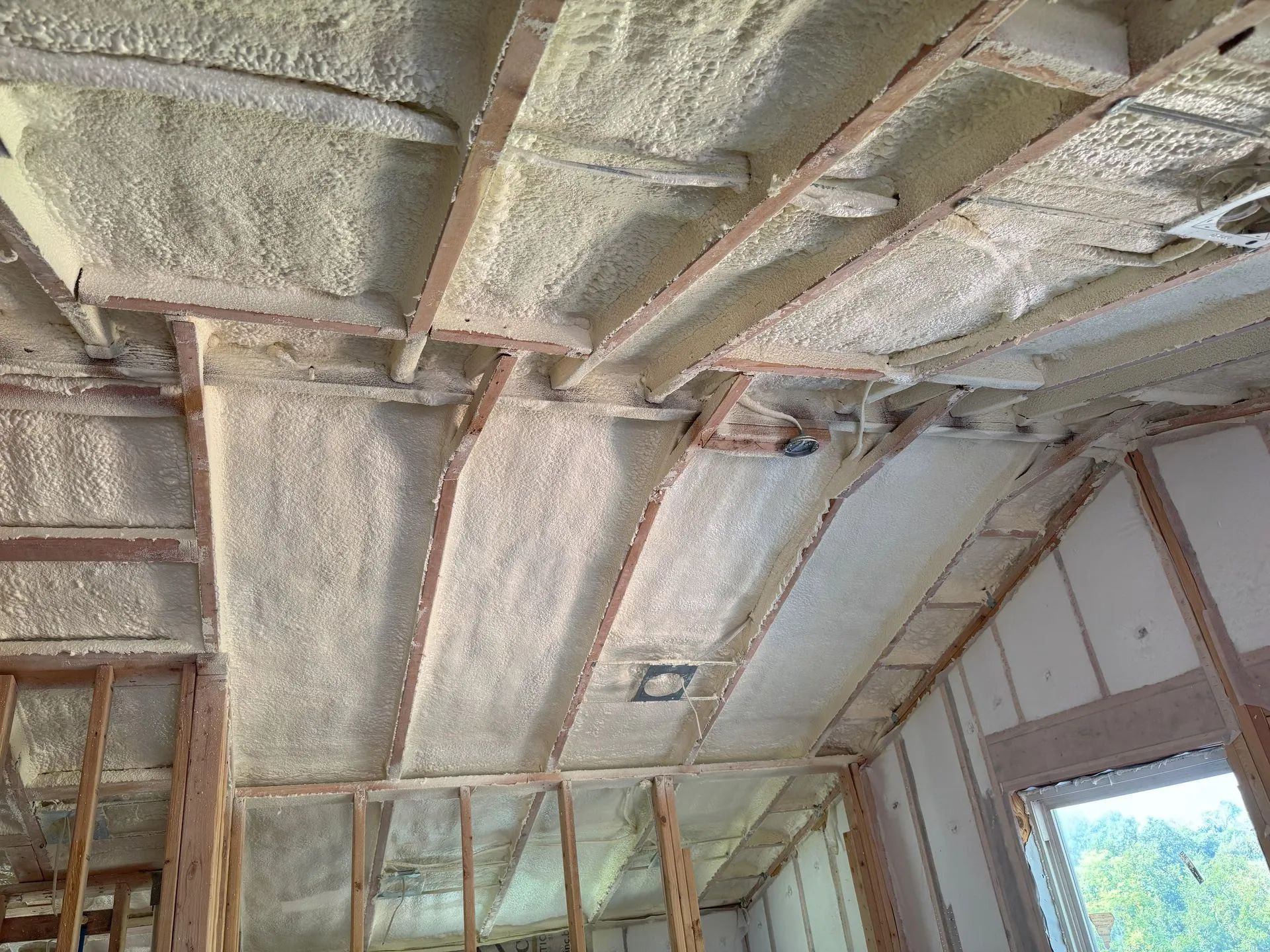 Insulated ceiling framing under construction with exposed beams and wall studs