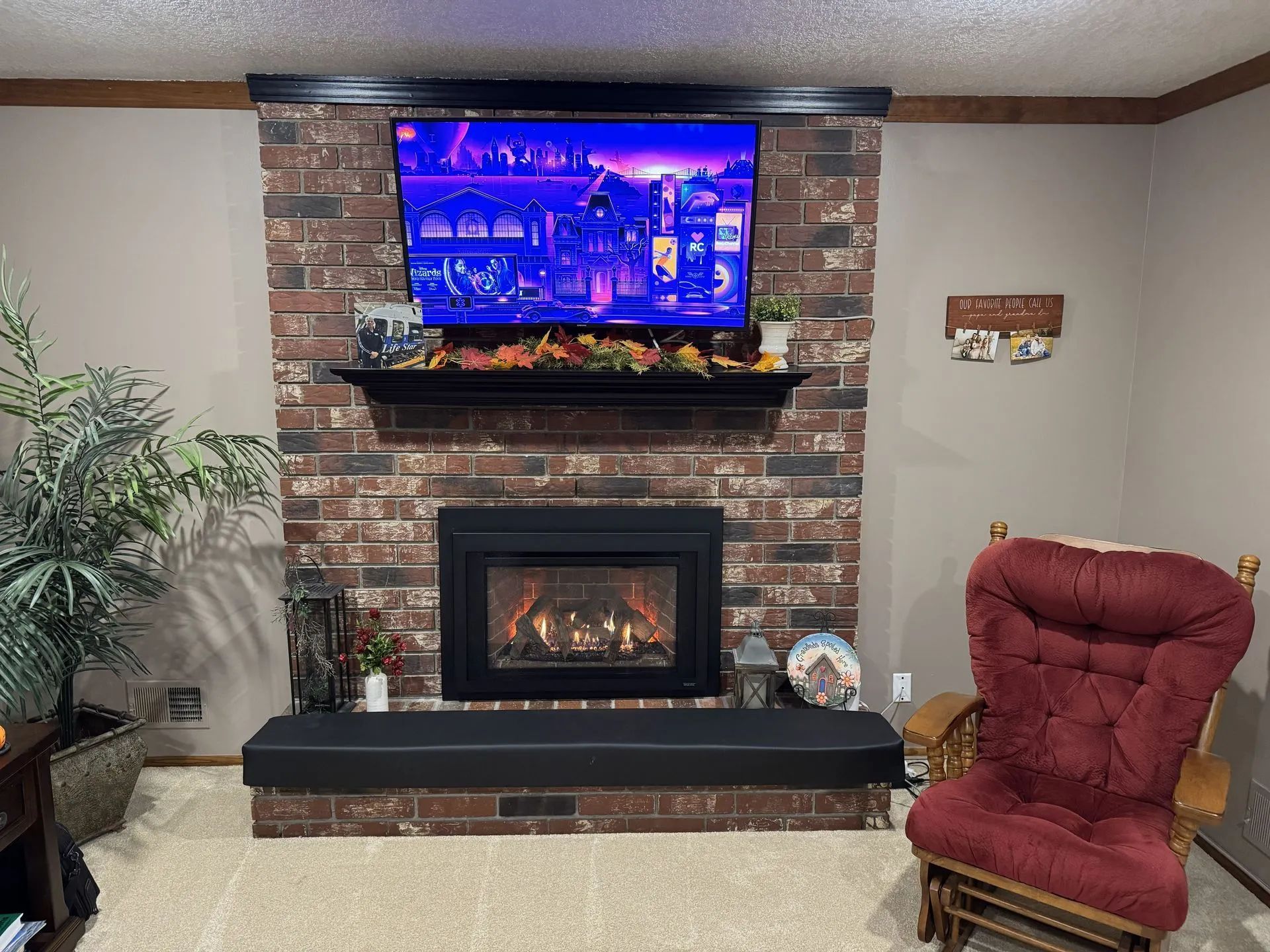 Living room fireplace with brick surround, wall-mounted TV, and a red upholstered chair