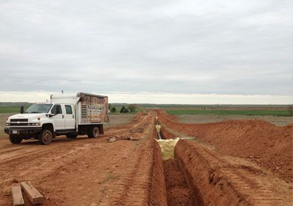 A white truck is parked on the side of a dirt road.