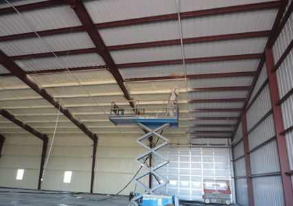 A man is standing on a scissor lift in a large building.