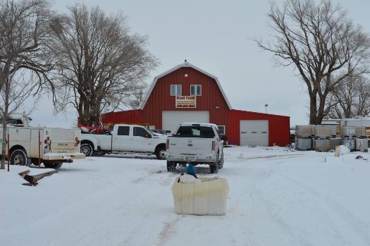 A red barn with a white truck parked in front of it