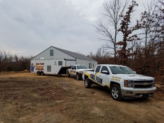 Two trucks are parked in front of a house and trailer.