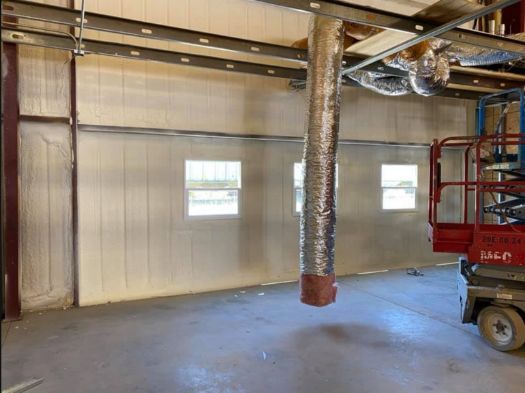 A red scissor lift is parked in a large empty room.