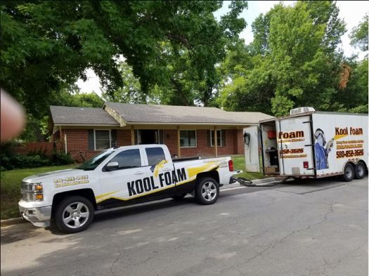 A truck and trailer are parked in front of a house.