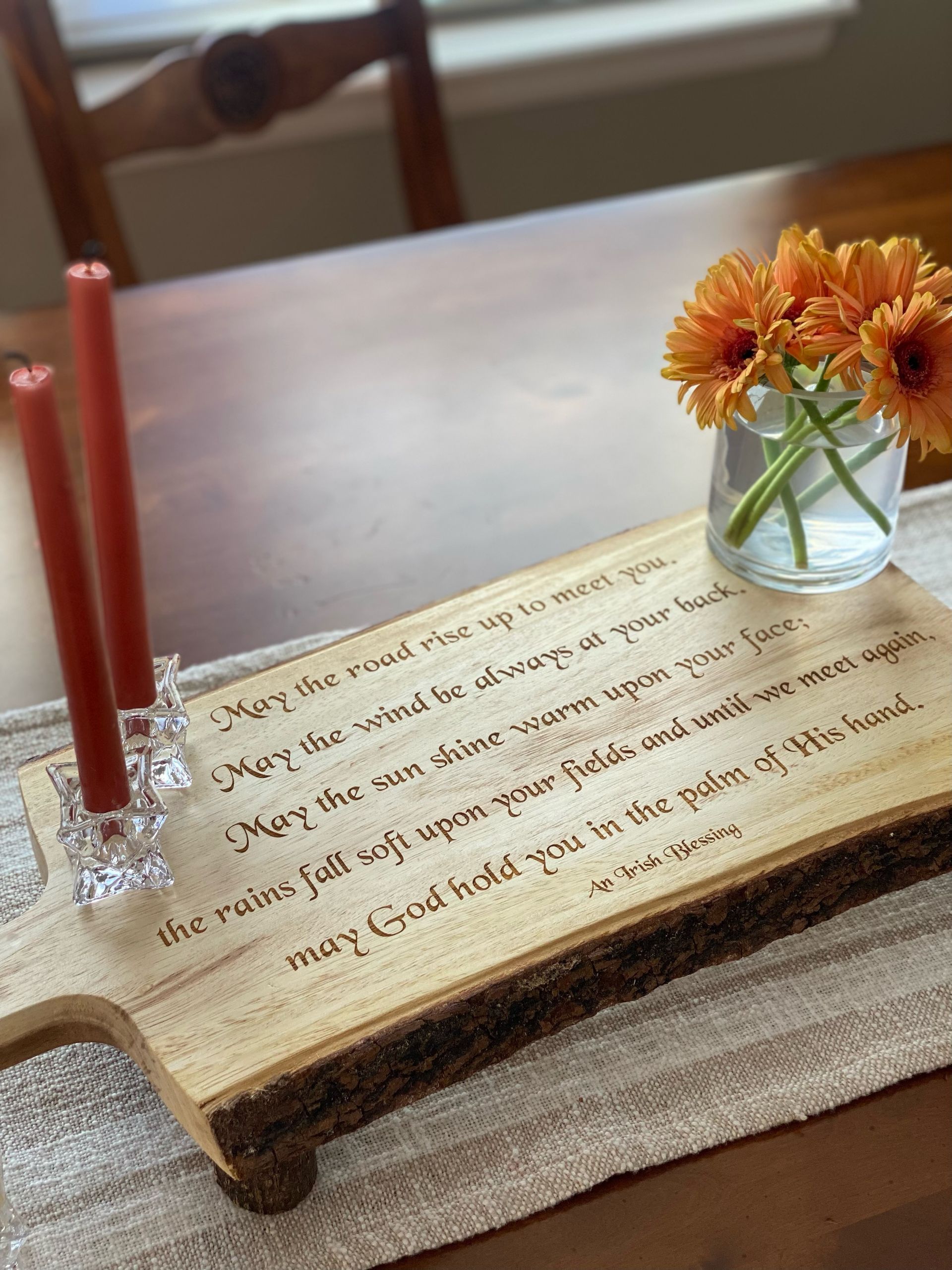 A wooden cutting board with candles and flowers on a table