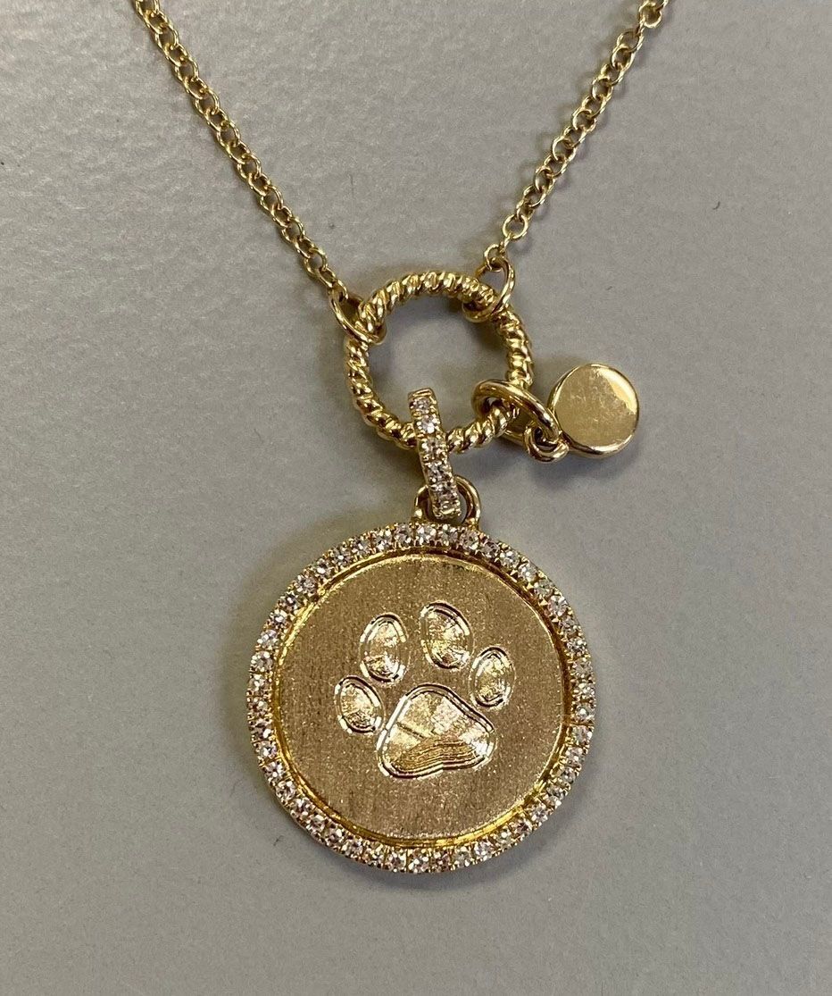 A gold necklace with a paw print on it