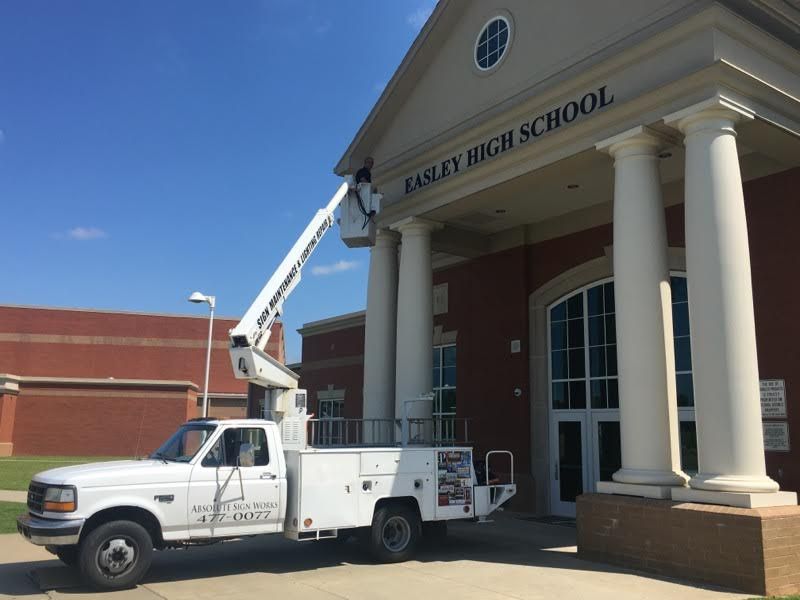 A white truck is parked in front of an eagles high school