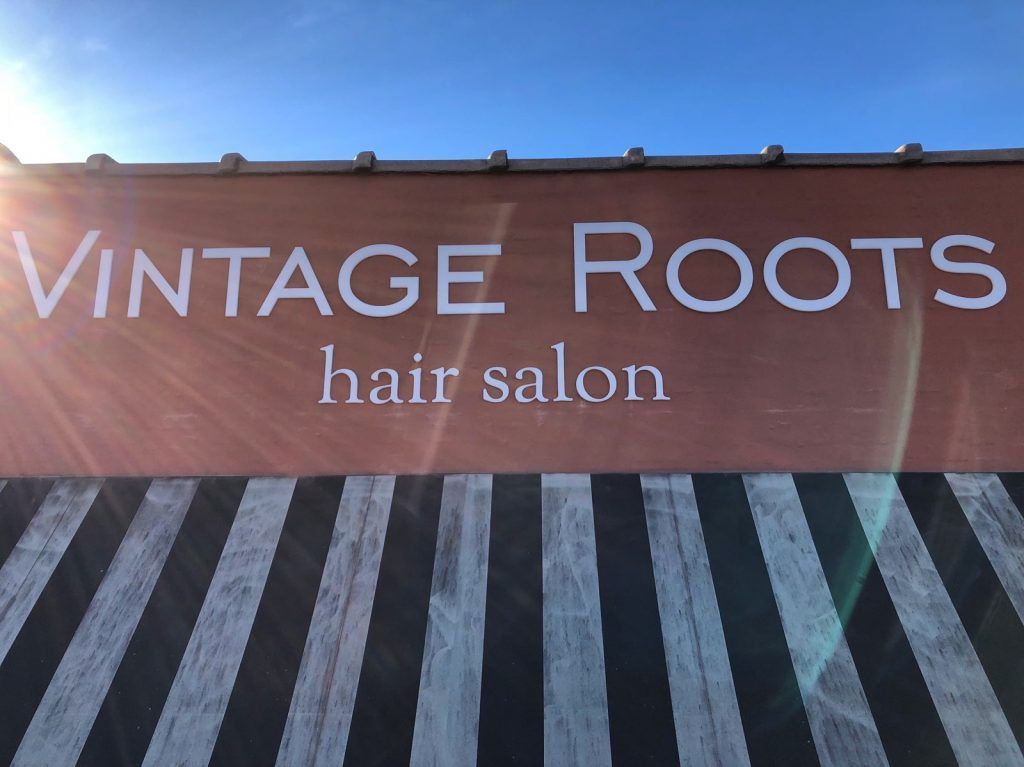 A sign for vintage roots hair salon is painted on a brick wall