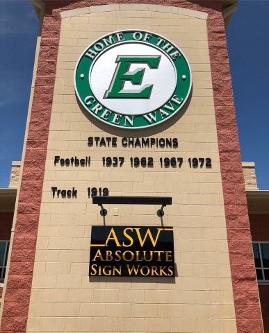 A brick building with a sign that says home of the green wave
