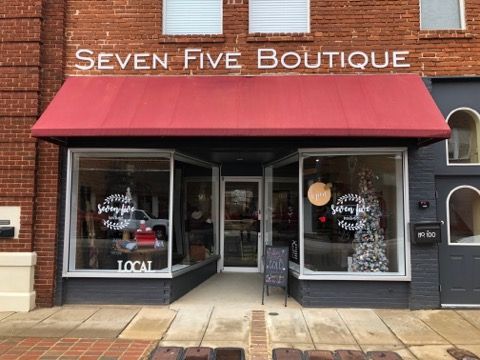 A brick building with a red awning that says seven five boutique