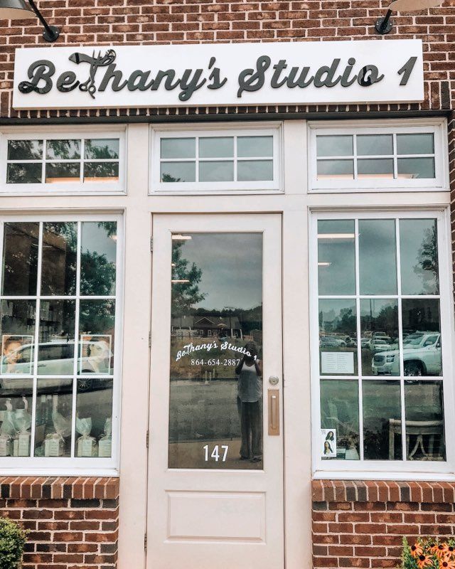 A brick building with a white door and a sign that says bethany 's studio 1