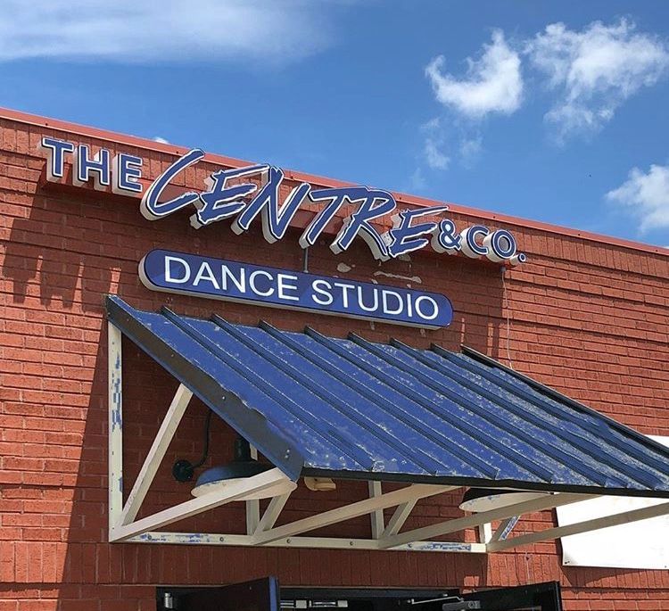 The front of a dance studio with a blue awning.