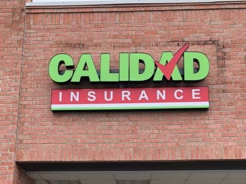 A sign for calidad insurance on a brick building