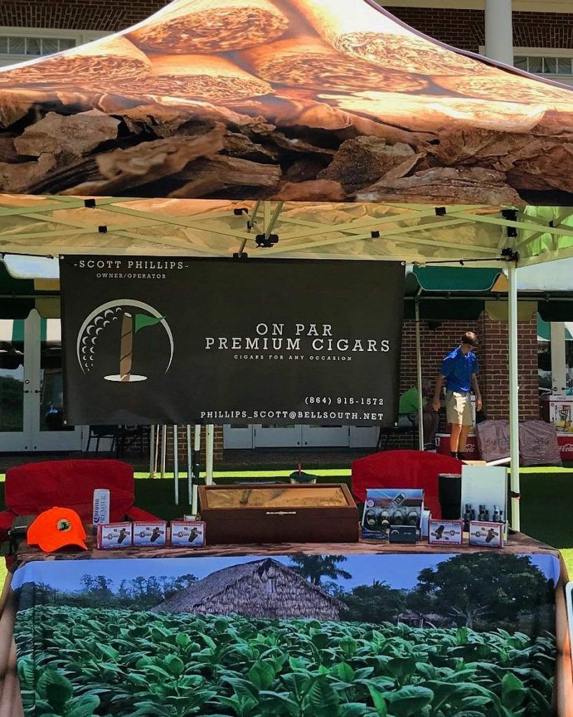 A man stands behind a table with a sign that says premium cigars