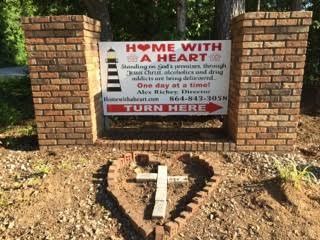 A sign that says `` home with a heart '' is on a brick wall.