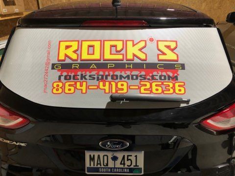 A black car with a sticker on the back window that says rock 's graphics