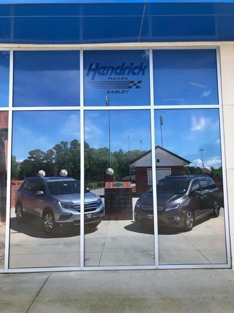 Two cars are parked in front of a hendrick dealership