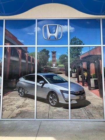 A honda car is reflected in the windows of a car dealership