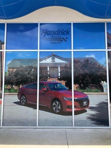 A red honda accord is displayed on the window of a car dealership.