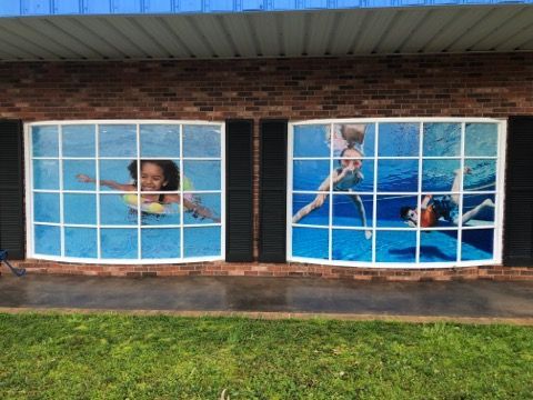 Two windows with pictures of people swimming in a pool on them.