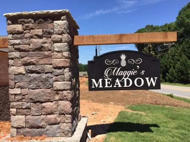 A sign that says maggie 's meadow on it