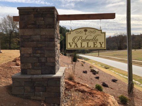 A palmetto valley sign is hanging from a brick pillar